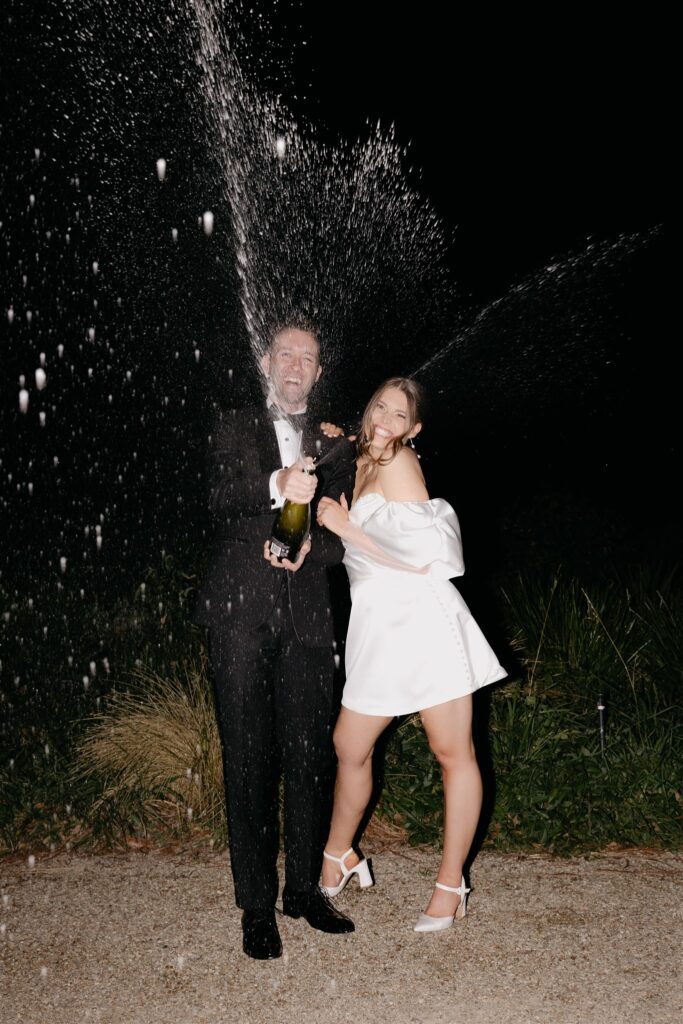 Wedding couple popping champagne at Harriet by Hubert Estate Wedding